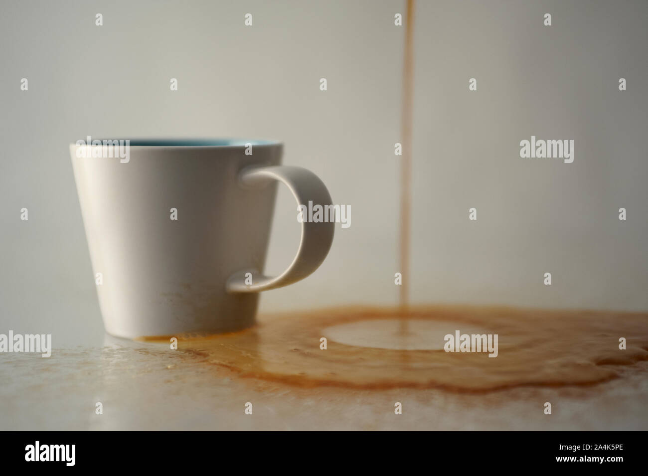 La fuoriuscita di caffè accanto a una tazza Foto Stock