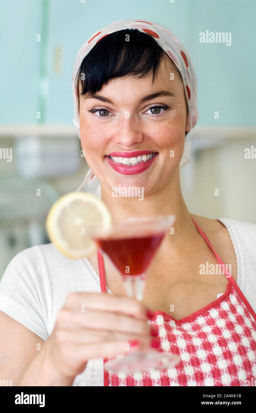 Donna che indossa il grembiule azienda bicchiere da cocktail Foto Stock