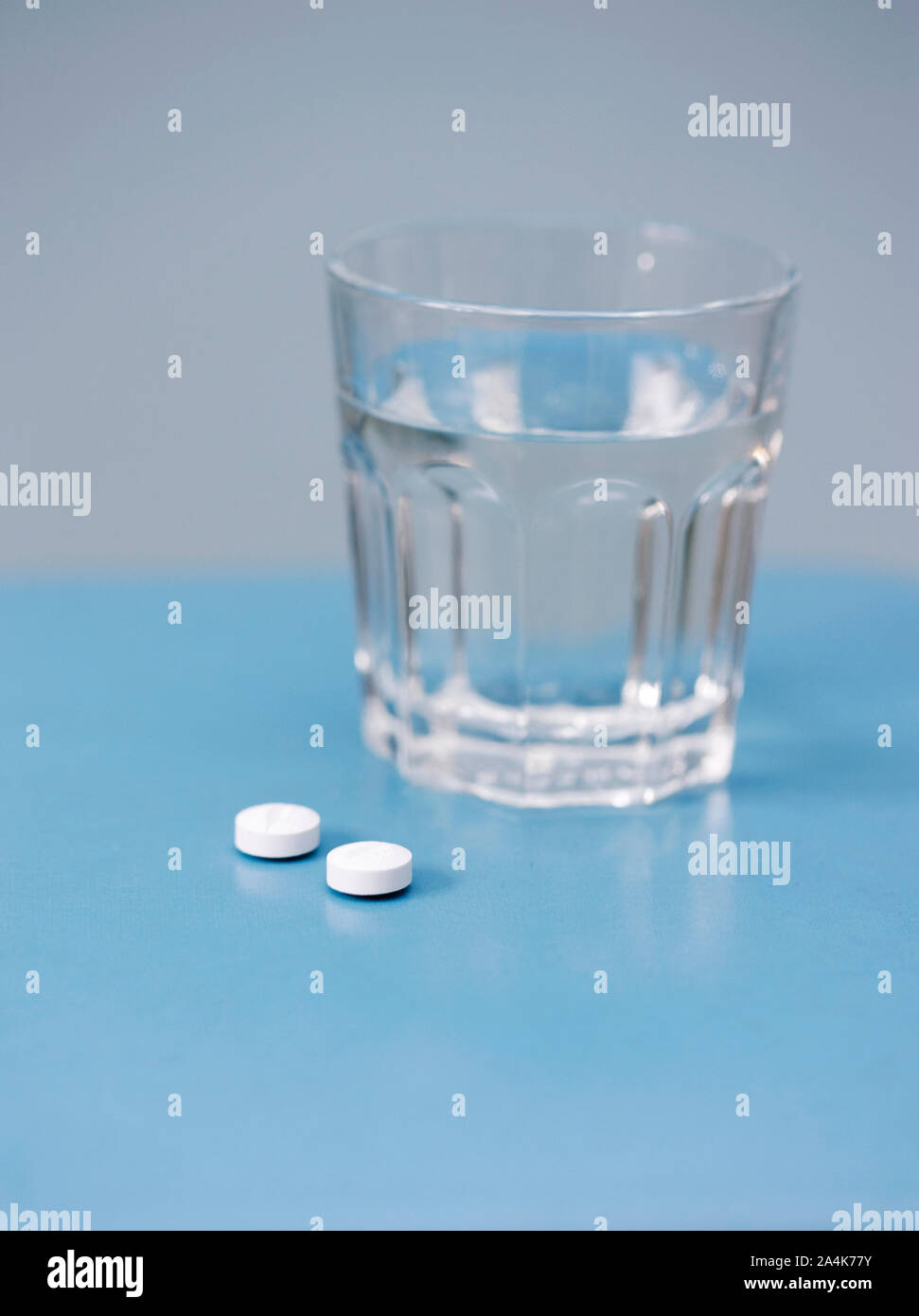 Pillole e un bicchiere di acqua Foto Stock