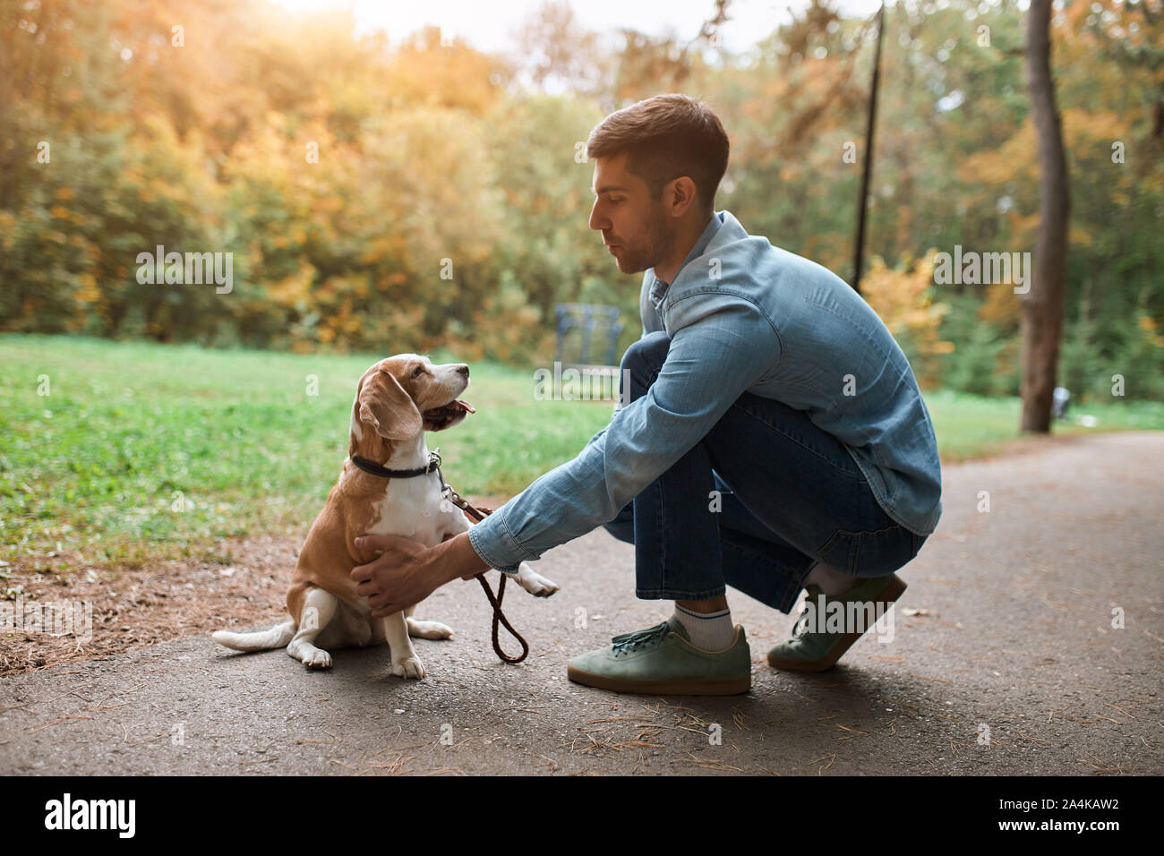 Giovane uomo bello insegnare il suo cane a stare su due gambe, zampe, istruzione, fulllength vista laterale foto Foto Stock