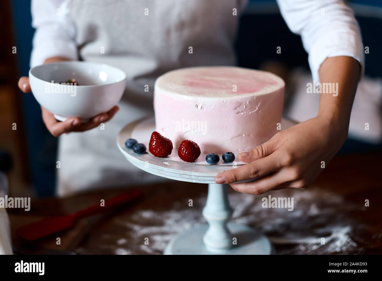 Lo chef tenendo un recipiente con frutti di bosco, rendendo torta per matrimonio. close up foto ritagliata Foto Stock