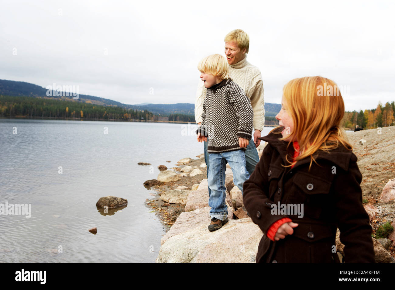 Famiglia lanciare pietre nel lago in Norvegia Foto Stock