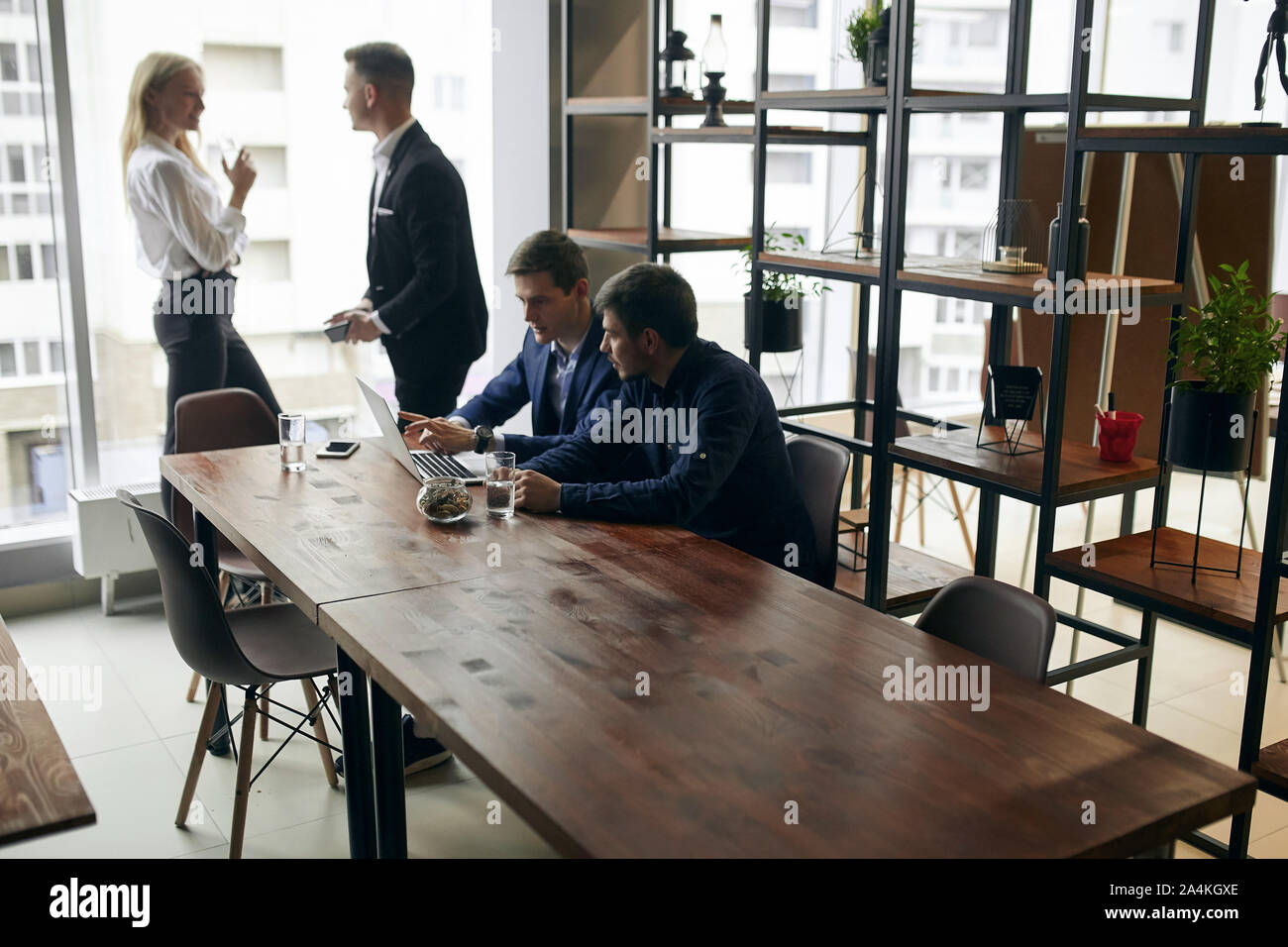 I giovani in abiti formali sono trascorrere il tempo in ufficio con arredamento moderno. Foto Stock