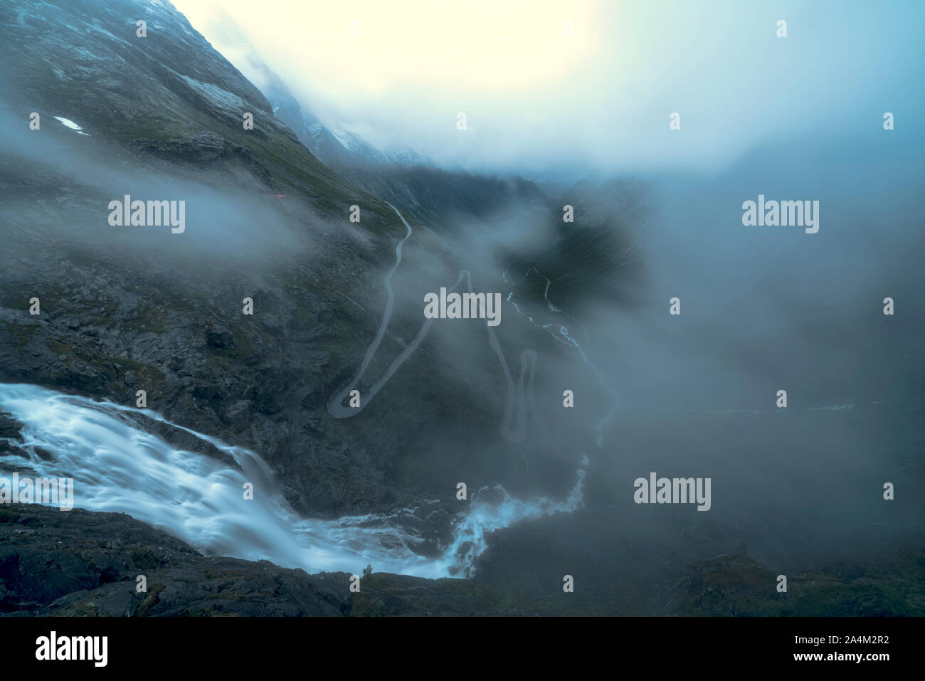La nebbia oltre la cascata e serpeggiante strada di montagna di Trollstigen, Rauma comune, Norvegia Foto Stock