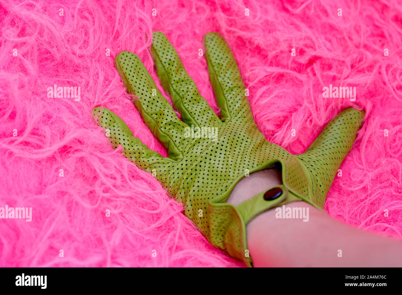 Green Glove toccando pink carpet/tessile in auto Foto Stock