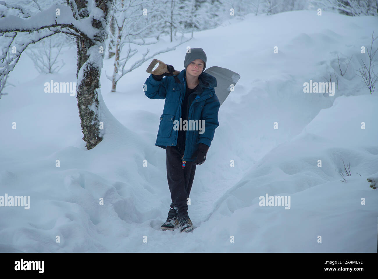Ragazzo in piedi con la pala in paesaggio invernale Foto Stock