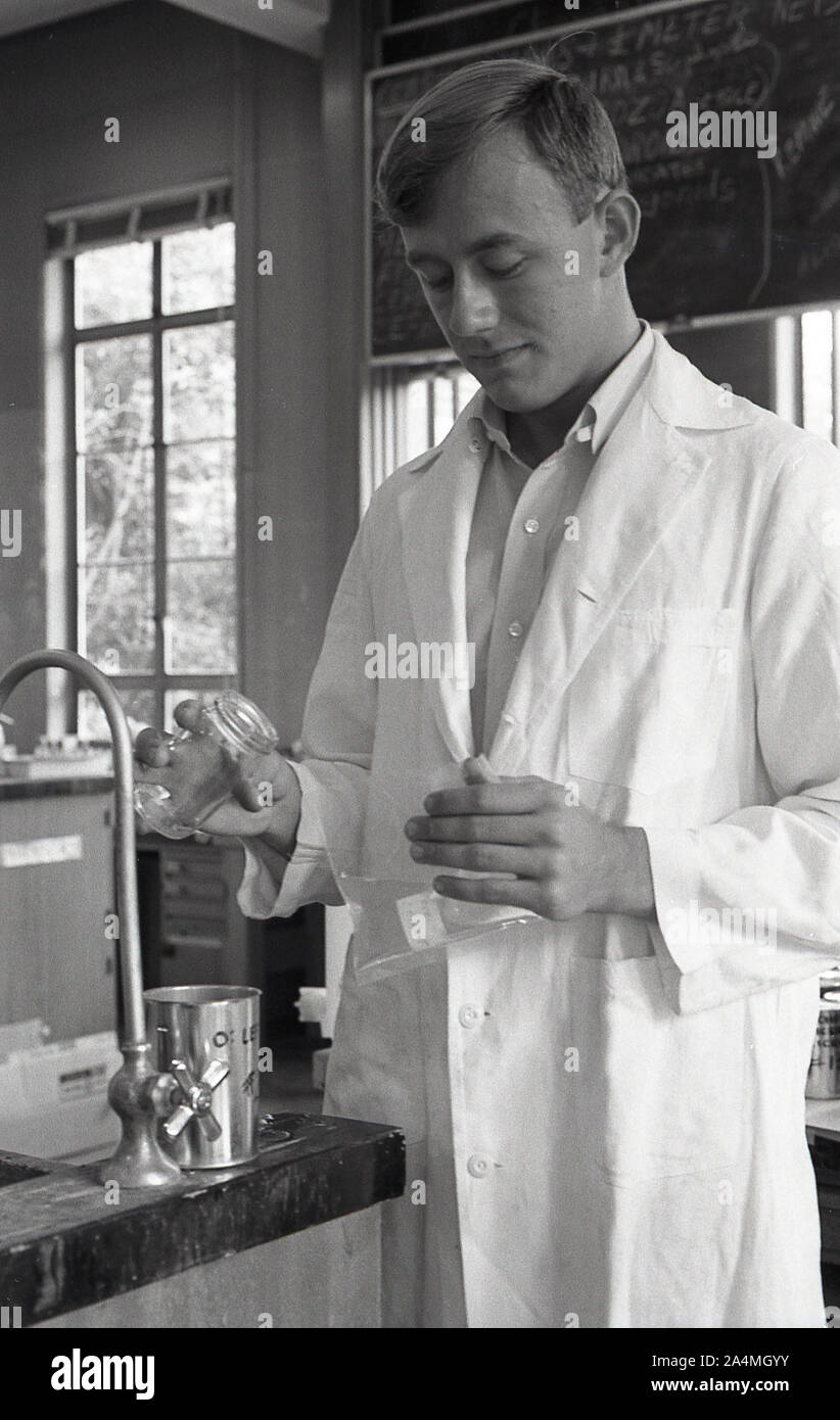 1960, storico, uno studente maschile che indossa un cappotto bianco e mescola fluidi in un laboratorio chimico presso la University of Southern California, USA. Foto Stock