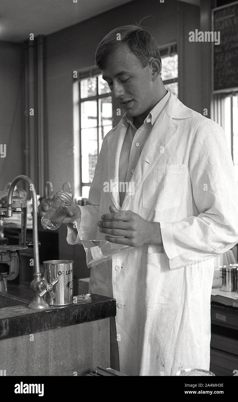 1960, storico, uno studente maschile che indossa un cappotto bianco e mescola fluidi in un laboratorio chimico presso la University of Southern California, USA. Foto Stock