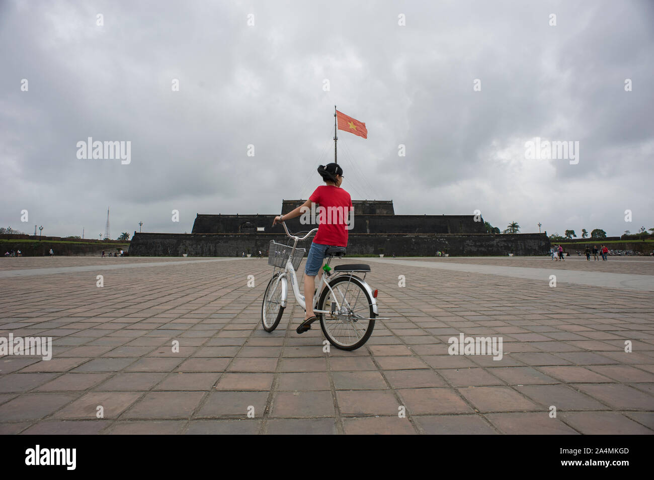 Tinta, Thua Thien-Hue, Vietnam - Febbraio 27, 2011: una ragazza vietnamita con maglietta rossa in bicicletta in una bicicletta Bianchi in bandiera Torre (Cot Co) square Foto Stock