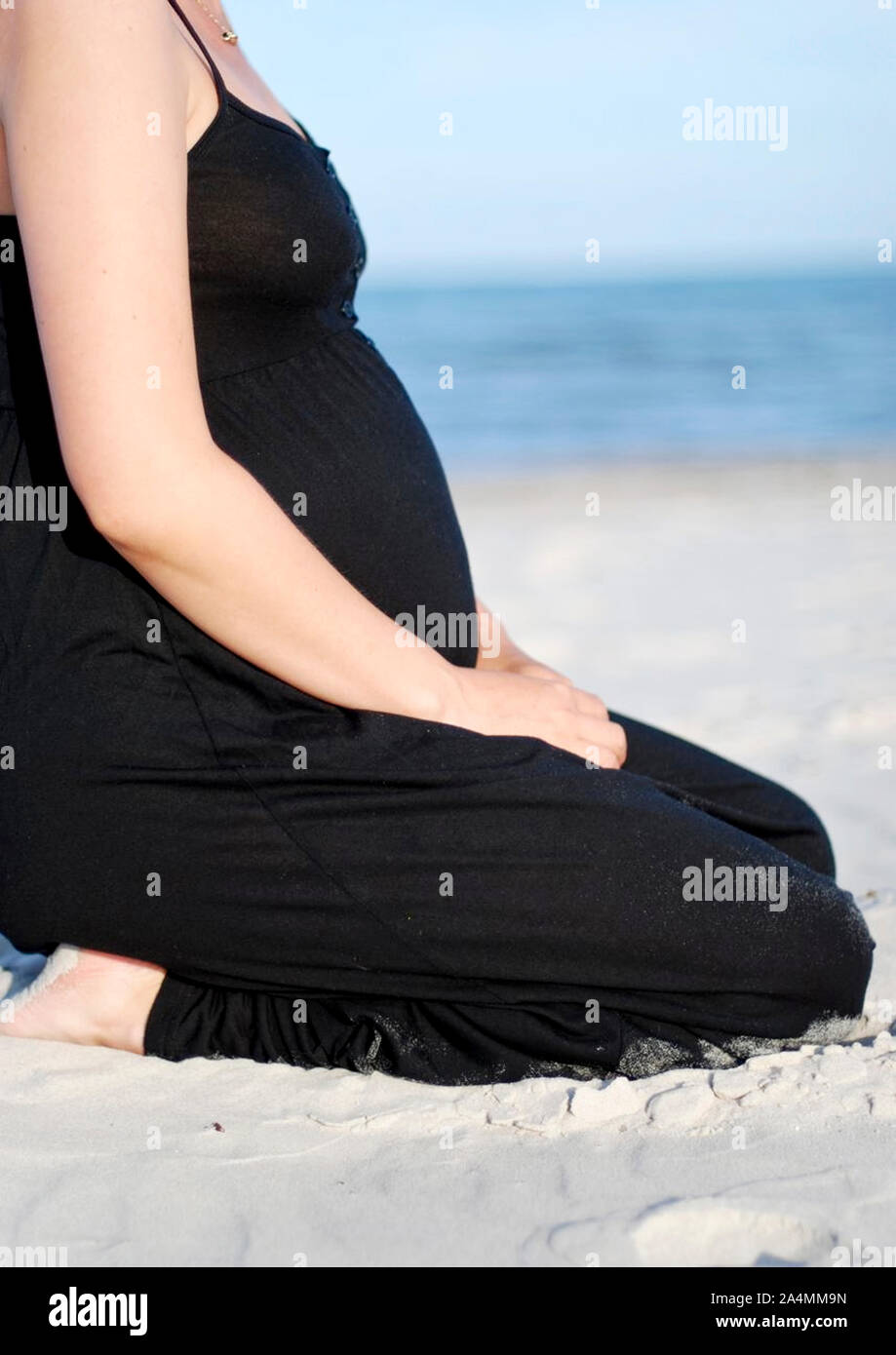 Donna incinta sulla spiaggia sabbiosa Foto Stock