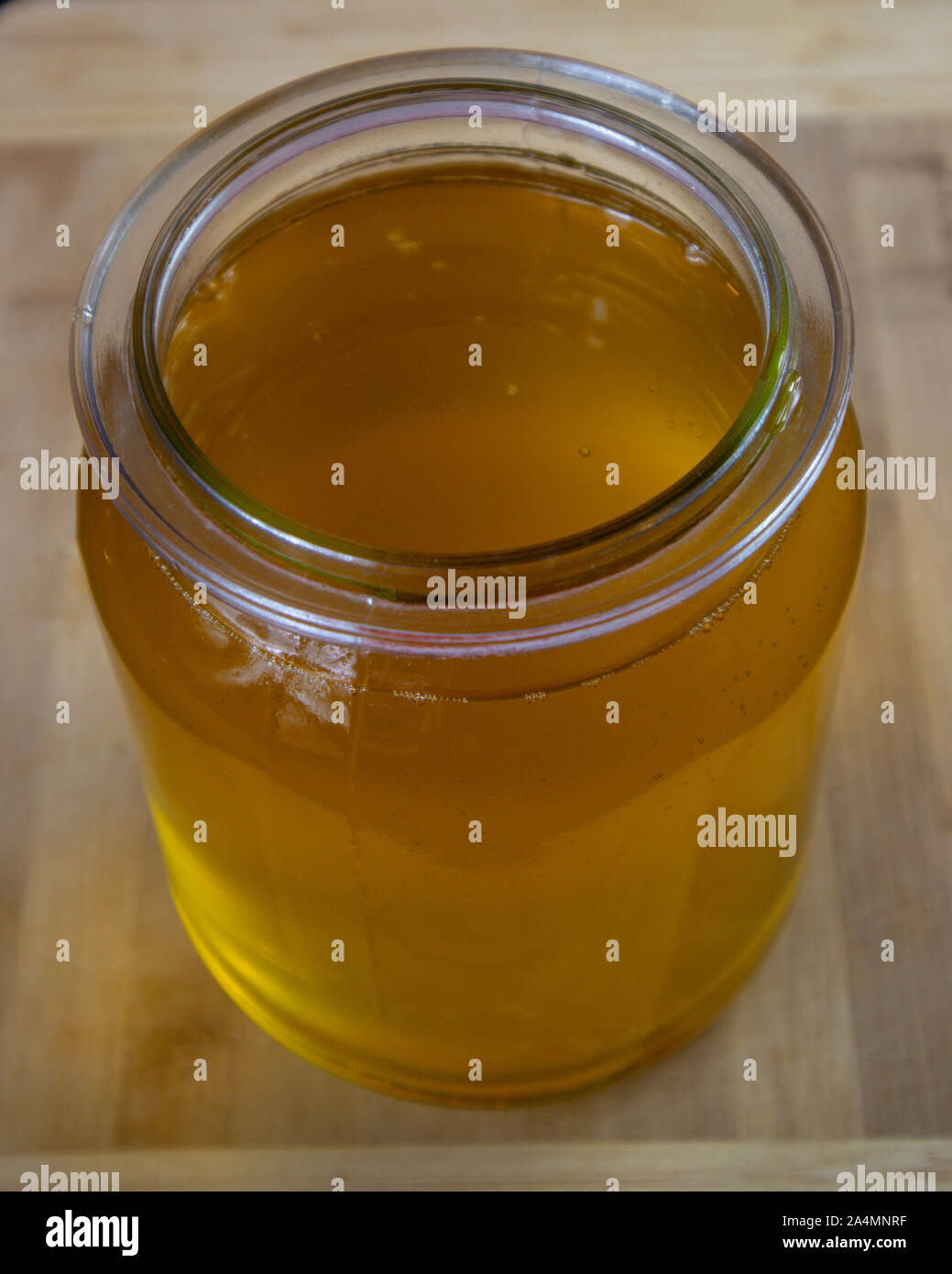 Il chiarimento di burro. Vaso pieno di burro chiarificato su uno sfondo di legno. Foto Stock
