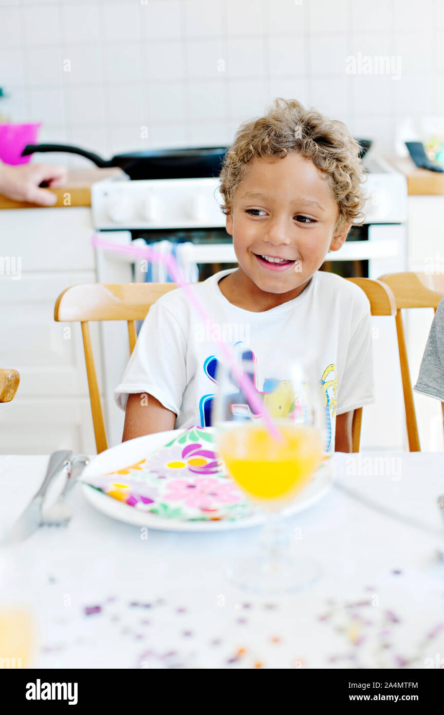 Ragazzo sorridente a tavola Foto Stock