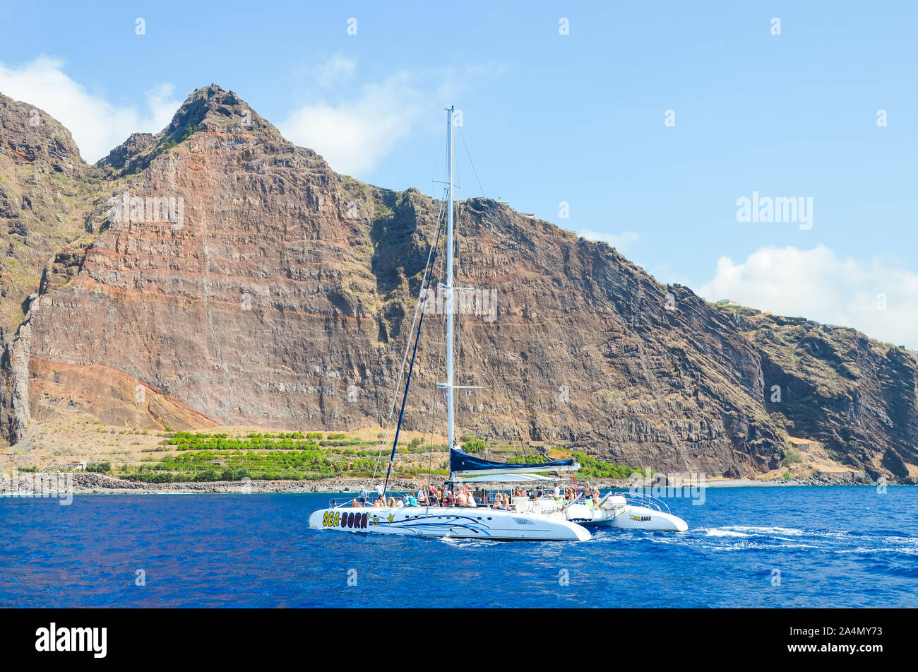 Madeira, Portogallo - Sep 10, 2019: visite turistiche barca con persone nelle acque dell'Oceano Atlantico. Rocce sull'isola di Madera in background. Avvistamento Balene, delfini viaggi. Foto Stock