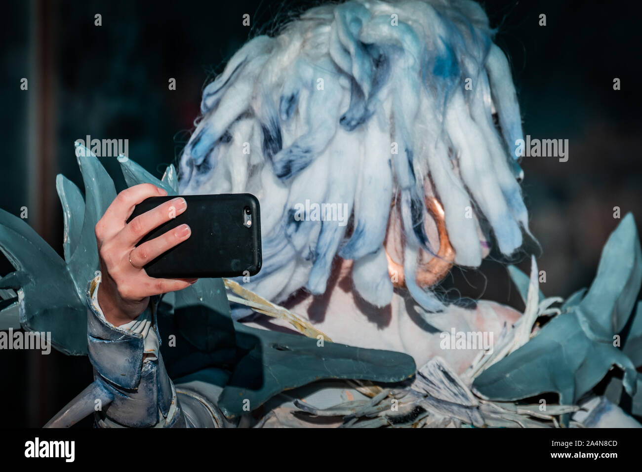 Selfie Zombie. Bianco morto nevoso regina costume, cosplayer ragazza con uno smartphone verso di sé. La luce naturale del giorno, ora d'oro di ripresa macro. Foto Stock