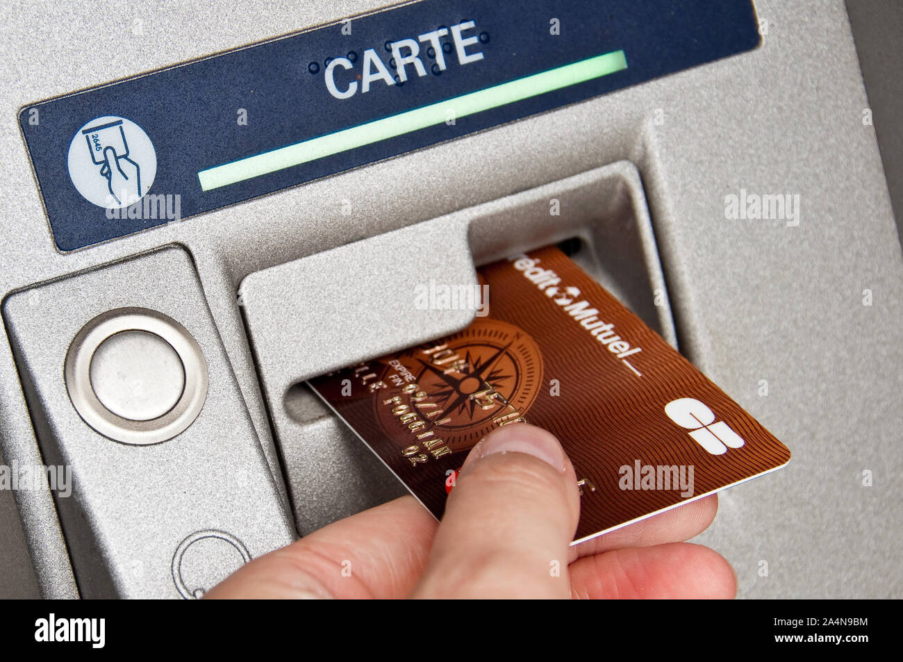Primo piano di una mano che tiene un francese di carta di credito in un ATM cash dispenser Foto Stock