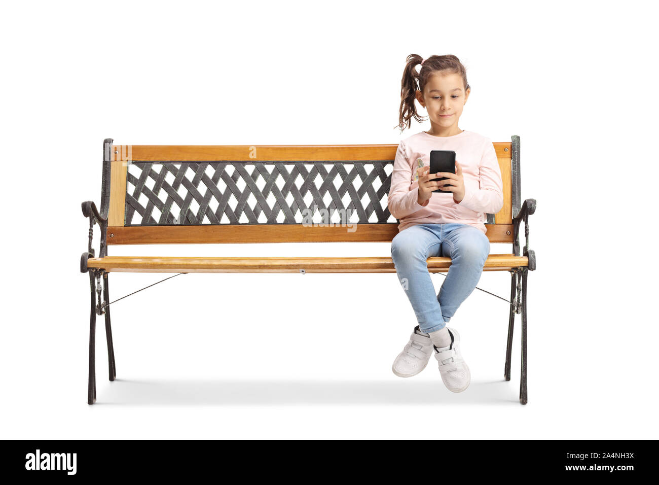 A piena lunghezza Ritratto di una bambina seduta su una panchina e giocare su uno smartphone isolati su sfondo bianco Foto Stock