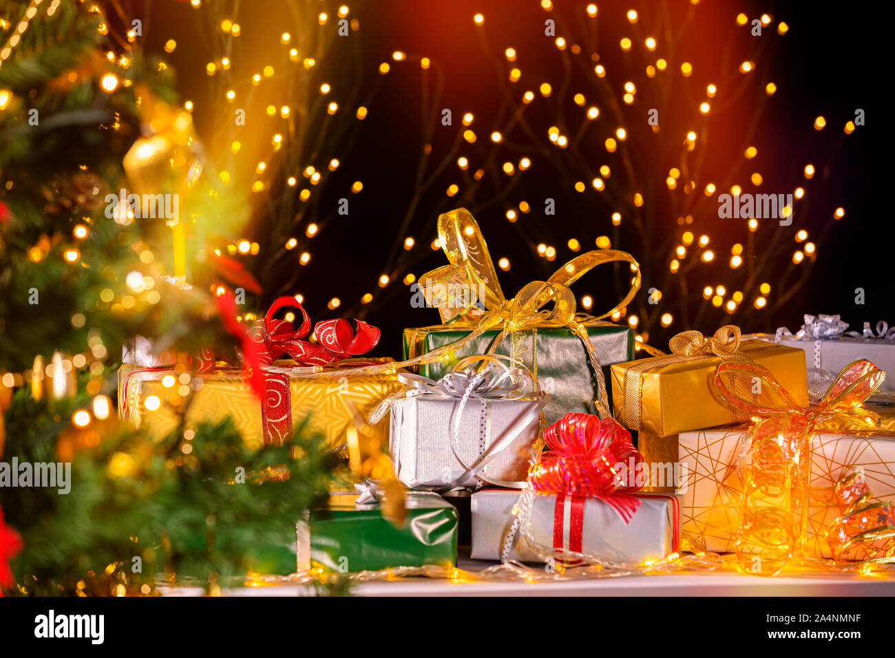 Pila di imballaggio di confezioni regalo sotto albero di Natale contro le particelle di luci. Un sacco di regali di Natale sotto l'albero. Il fuoco selettivo sulla green box regalo! Foto Stock