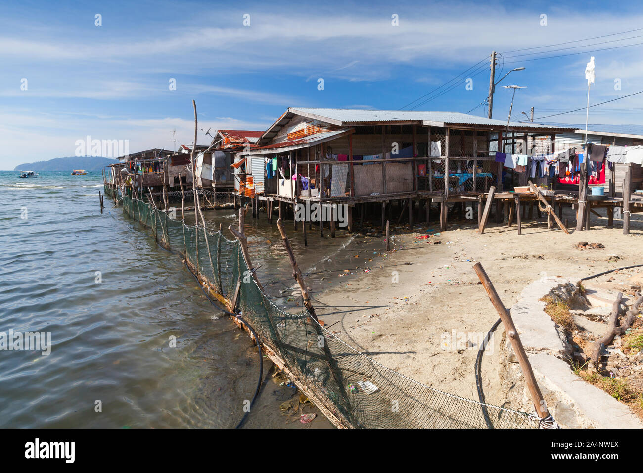 Case in legno e passerelle su palafitte. Povero quartiere costiero di Kota Kinabalu, Malaysia Foto Stock