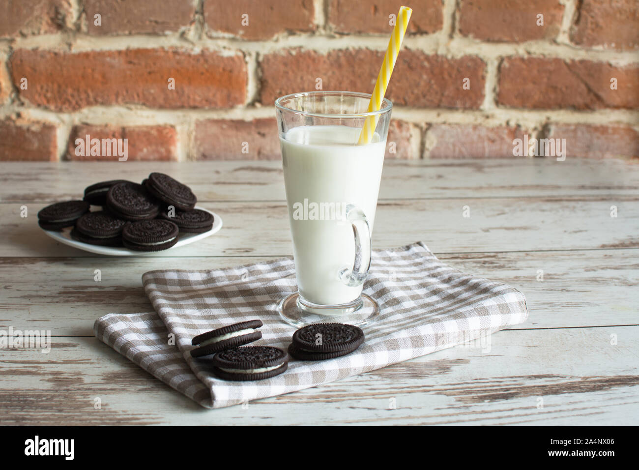 Dolci biscotti al cioccolato con crema vaniglia riempimento e un bicchiere di latte. Foto Stock