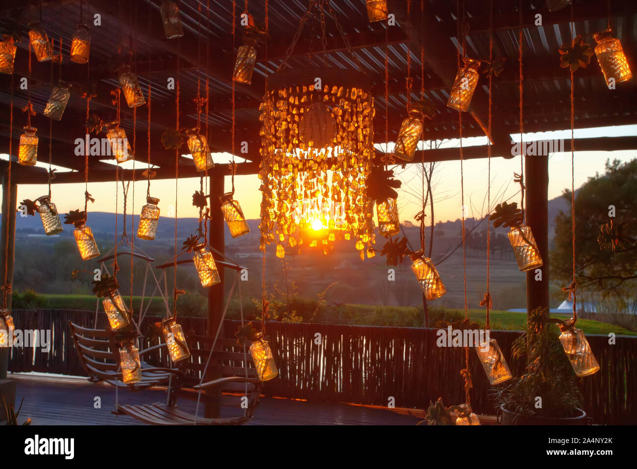 lampadario e bottiglie appese al veranda, tramonto africano con vista del bush Foto Stock