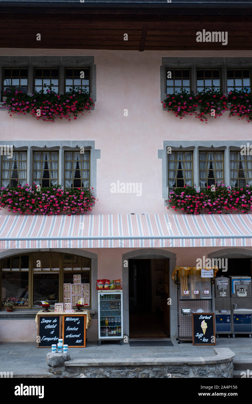 Appendere i fiori e il negozio nella città antica di Gruyère, Svizzera Foto Stock