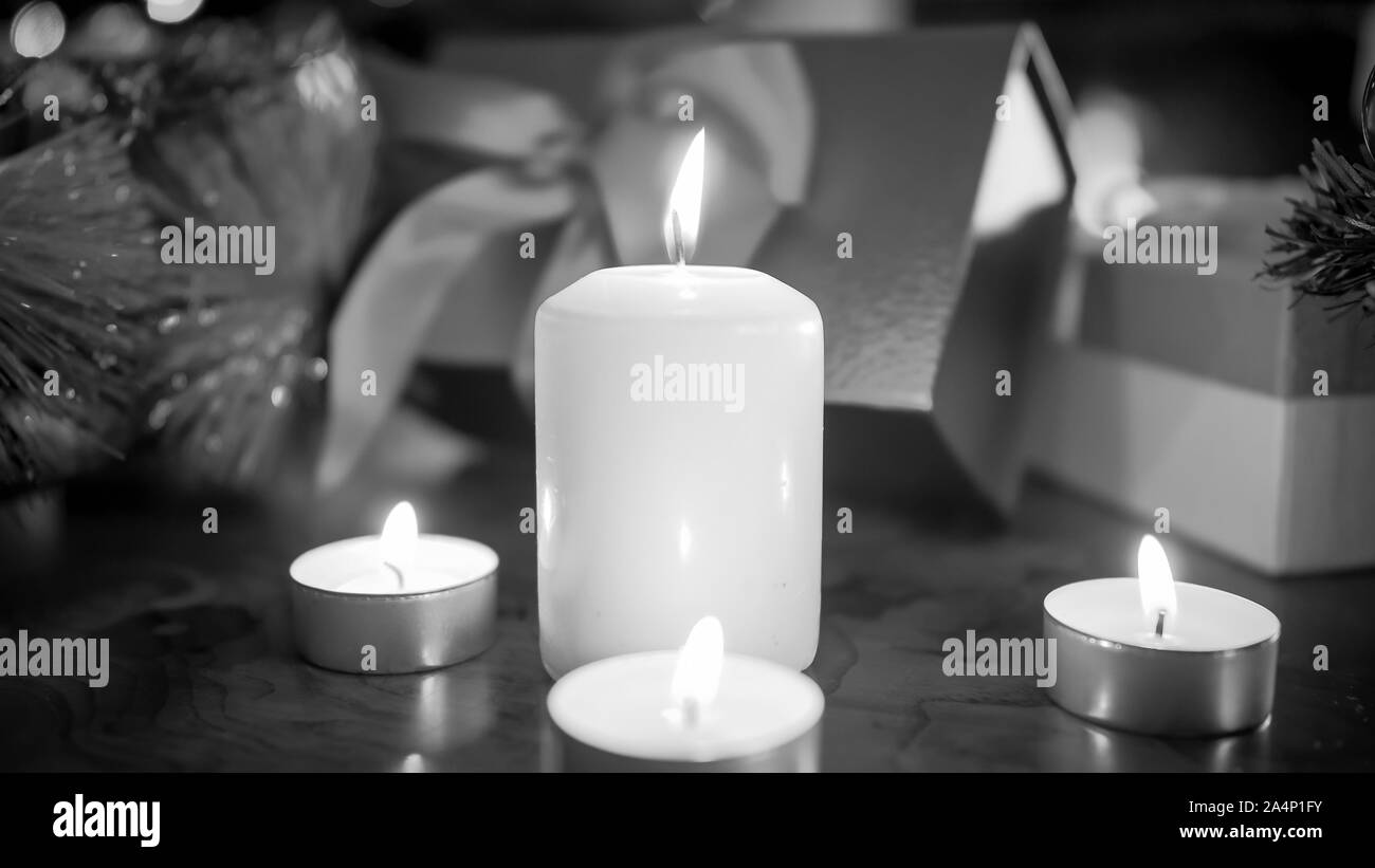 Primo piano immagine in bianco e nero di candele accese aginst regali di Natale e regali Foto Stock