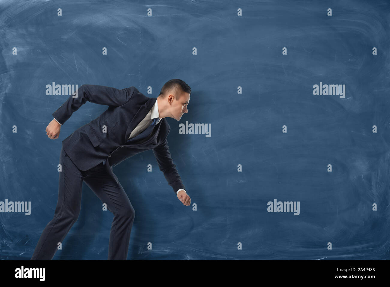 Imprenditore in piedi come se egli è andare a correre o di perseguire il suo obiettivo sulla lavagna blu sullo sfondo. Foto Stock