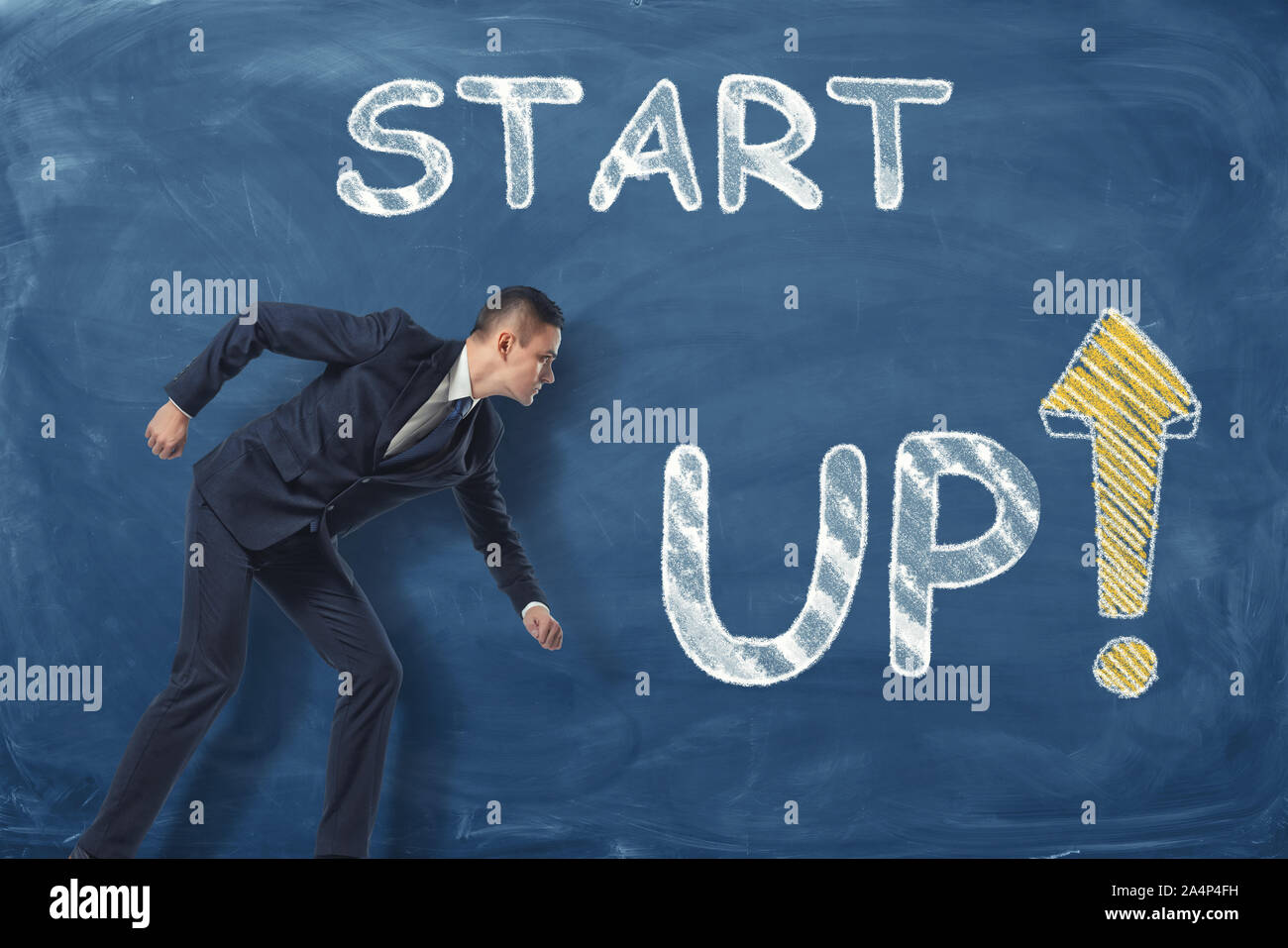 Imprenditore in piedi come se egli è andare a correre vicino la frase "start up" scritto sul blu scuro muro. Foto Stock