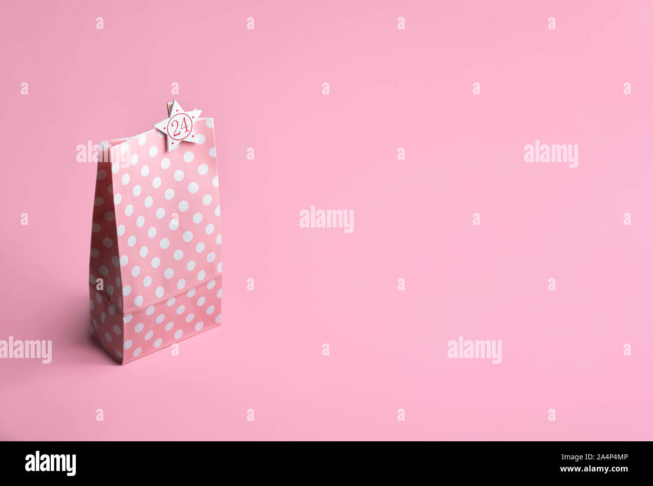 Regalo rosa sacchetto di carta con puntini bianchi e il numero 24, su un sfondo rosa. Natale calendario dell'avvento del concetto. La Vigilia di Natale il contesto. Gifting tema. Foto Stock