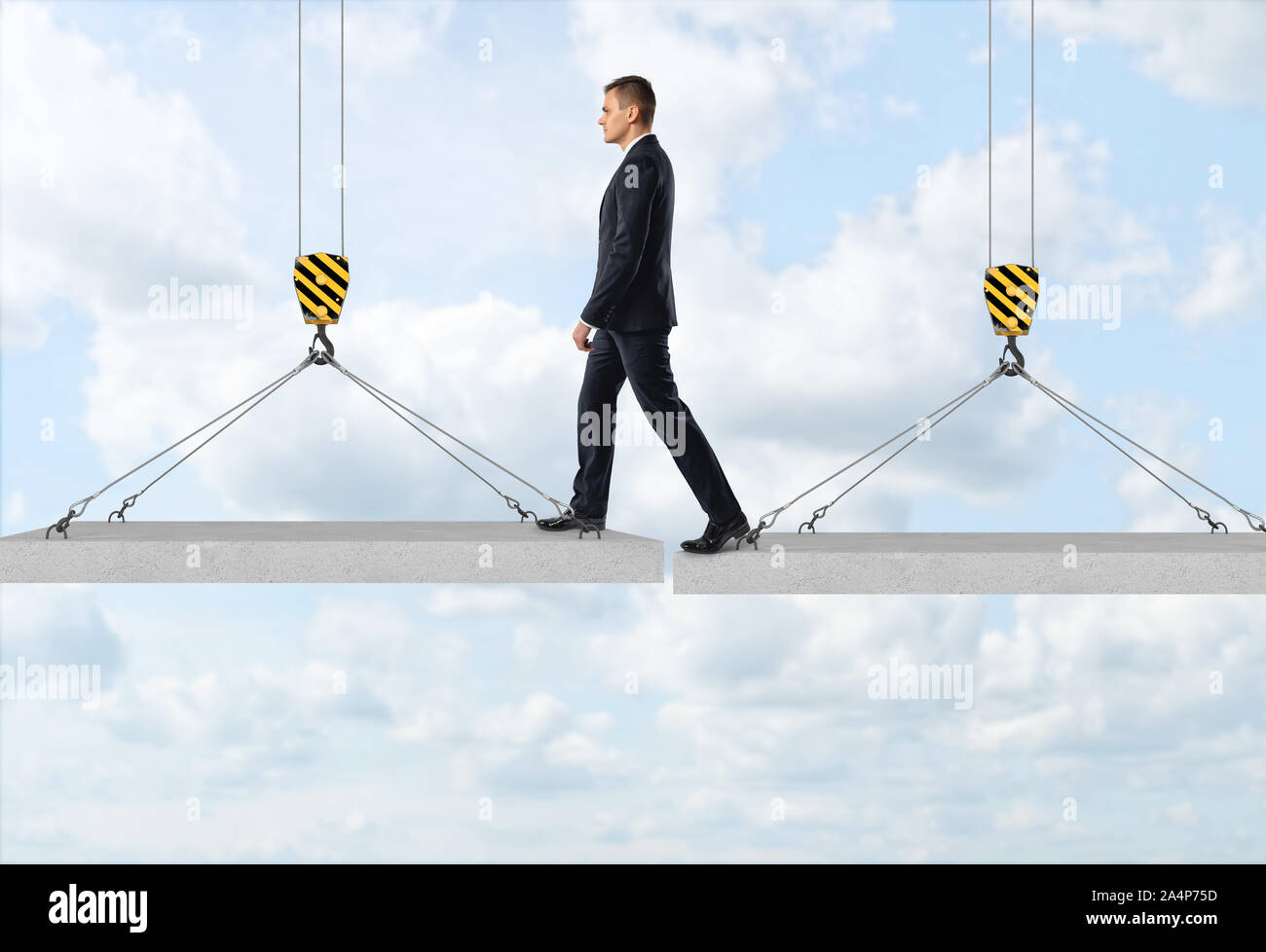 Imprenditore è a scavalcare un gap da un pannello in calcestruzzo ad un altro nell'aria sullo sfondo del cielo Foto Stock