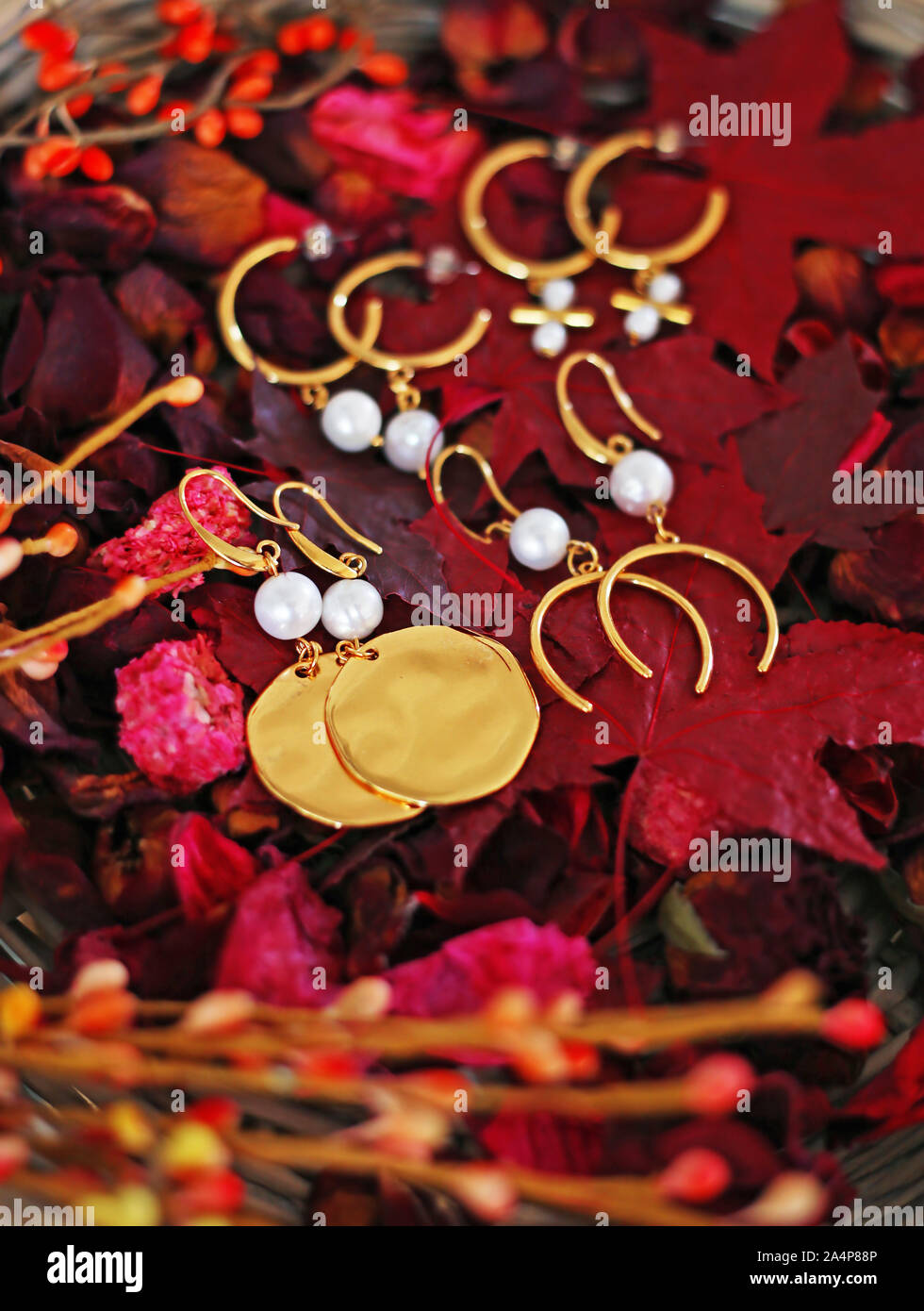 Orecchini in oro con perle su rosso Foglie di autunno - autunno moda e gioielli annuncio Foto Stock