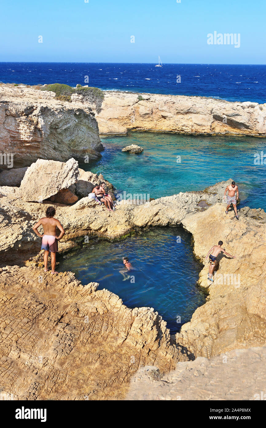 La gente di nuoto nella piscina naturale del mare tra le rocce a Ano Koufonisi isola Grecia Foto Stock