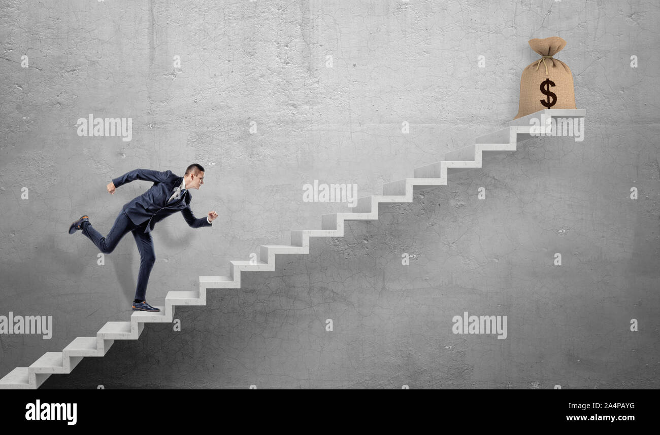 Un imprenditore in esecuzione su una scalinata in cemento con un legato hessian borsa con il segno del dollaro su di esso. Foto Stock