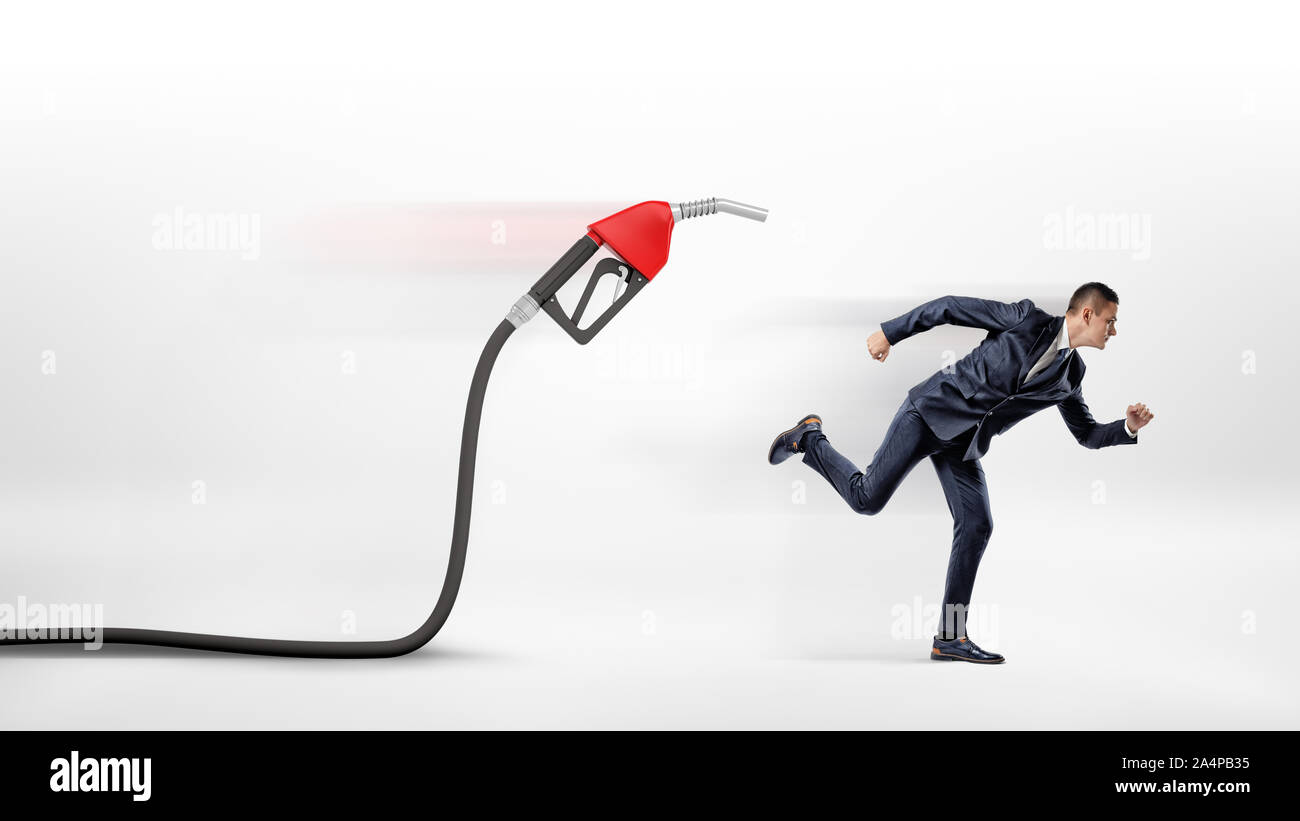 Un imprenditore su sfondo bianco di scappare da un gas di colore rosso ugello attaccata ad un tubo flessibile nero. Foto Stock
