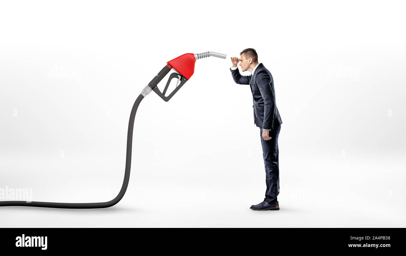 Un imprenditore su sfondo bianco fissando attentamente un grande rosso ugello di gas collegata ad un tubo flessibile nero. Foto Stock