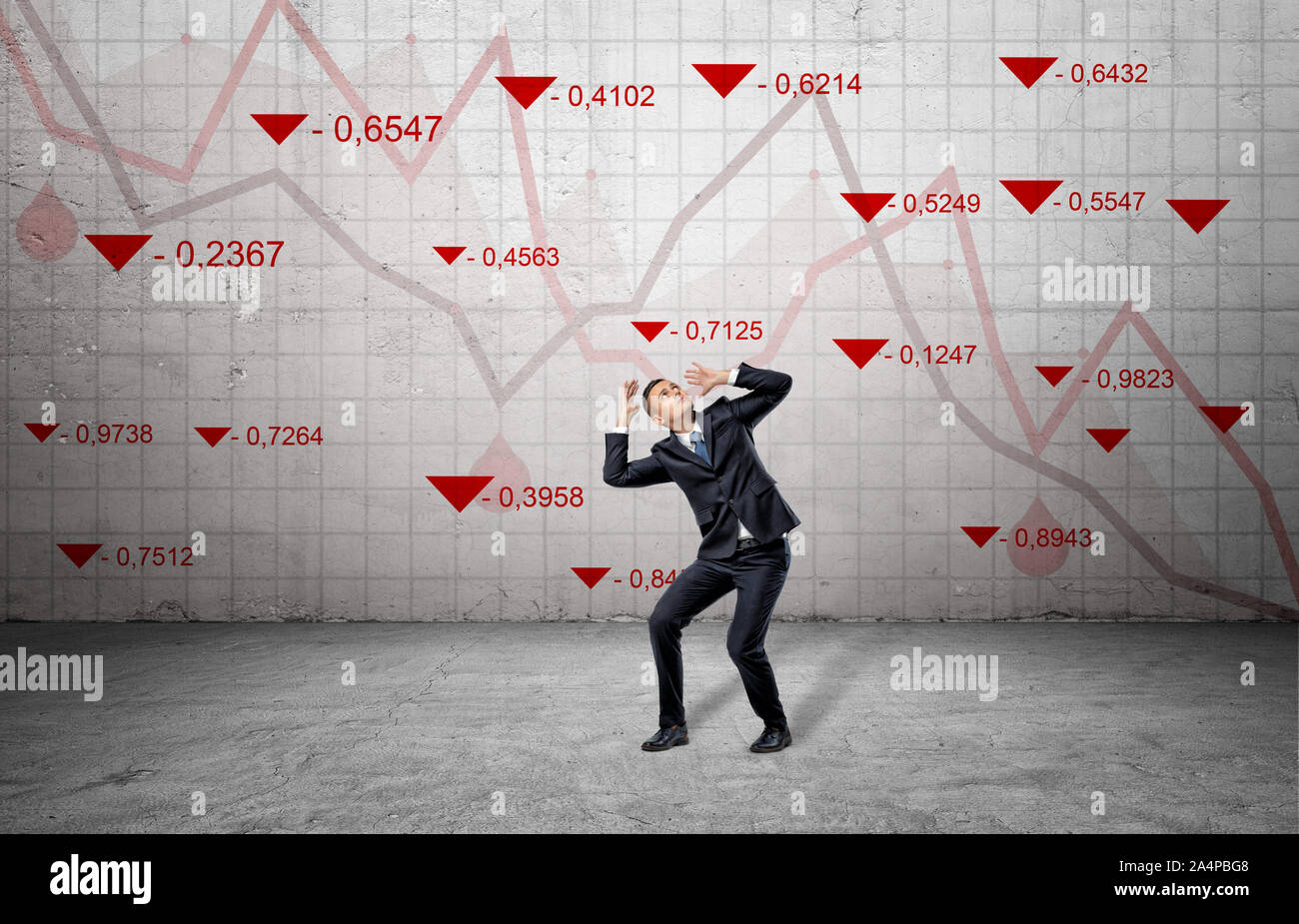Una paura imprenditore cowers vicino a un muro di cemento con stock di rosso gli indici di mercato e statistica di caduta delle linee. Foto Stock