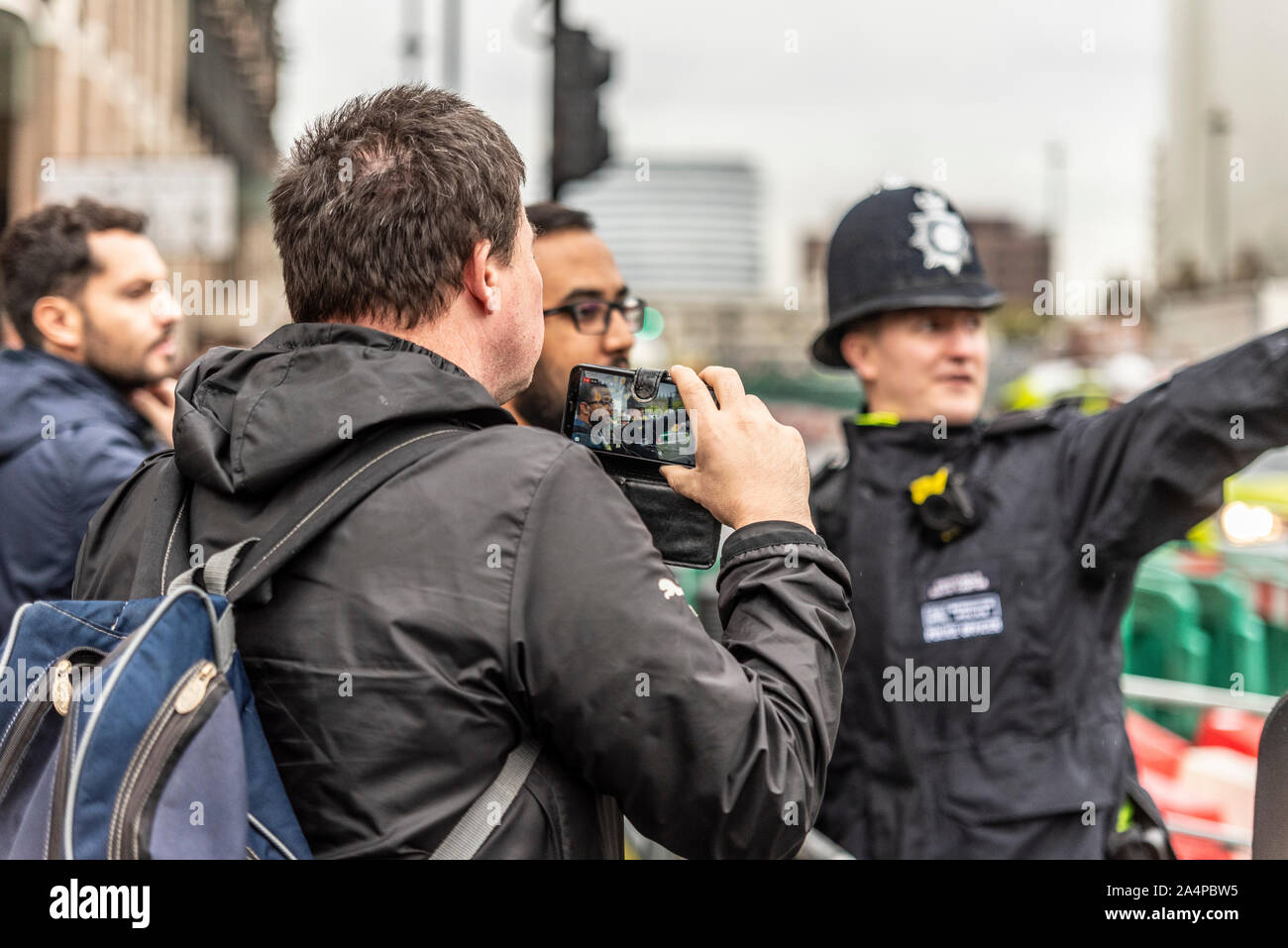 Bianco maschio caucasico di filmare un funzionario di polizia fermare lui di avvicinarsi al Parlamento prima della apertura della condizione del Parlamento Foto Stock