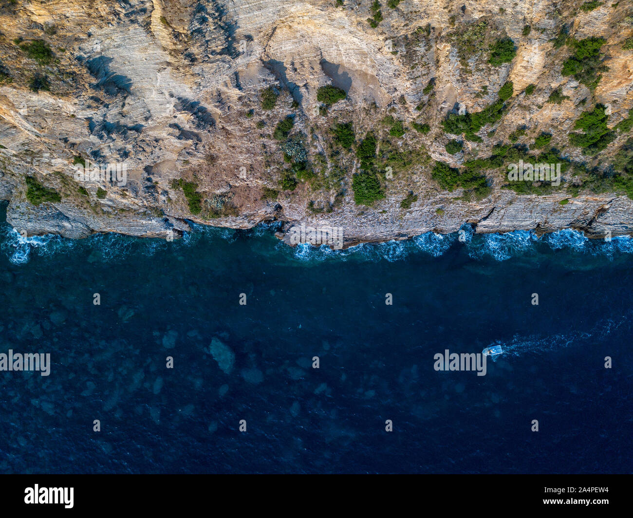 Vista aerea di una ripida scogliera e una barca a motore. Costa frastagliata sul Mare Adriatico. Scogliera che domina il mare trasparente. Natura selvaggia e Mediterraneo Foto Stock