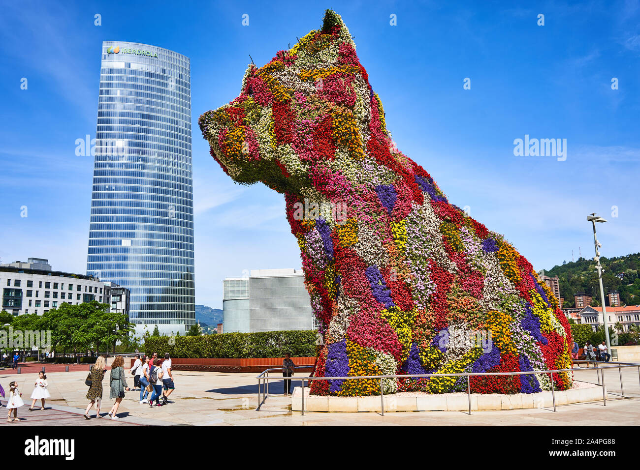 Vista laterale di Jeff Koons Puppy, la gigantesca scultura di terrier ricoperta di fiori, accanto alla Torre Iberdrola del Museo Guggenheim di Bilbao, Spagna Foto Stock