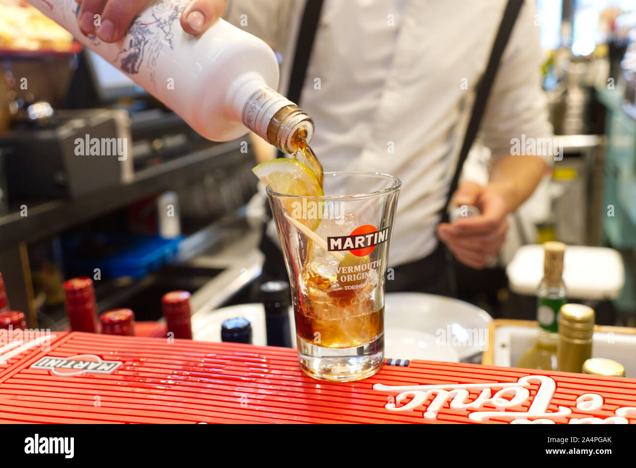 Un barman in una camicia bianca e bretelle versa un vermouth in bottiglia  in una coppetta Martini riempito con ghiaccio, l'oliva e una fetta di  agrumi Foto stock - Alamy