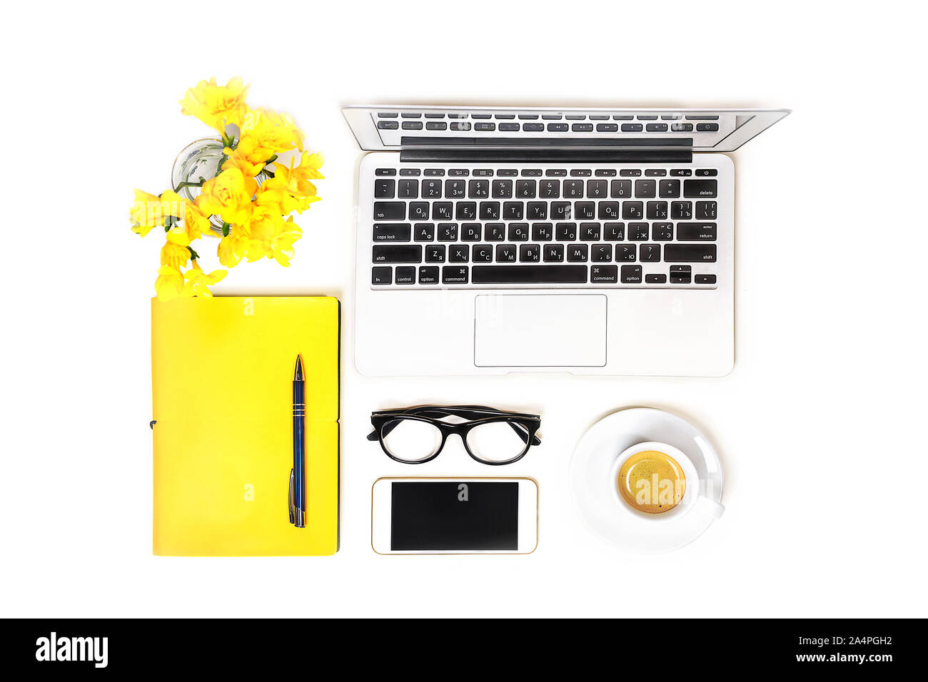 Area di lavoro con computer laptop notebook, moda occhiali, tazza di caffè, telefono cellulare, e fiore giallo, notebook con penna su sfondo bianco, isolata. Vista dall'alto. Lay piatto. Il concetto di shopping online. Foto Stock