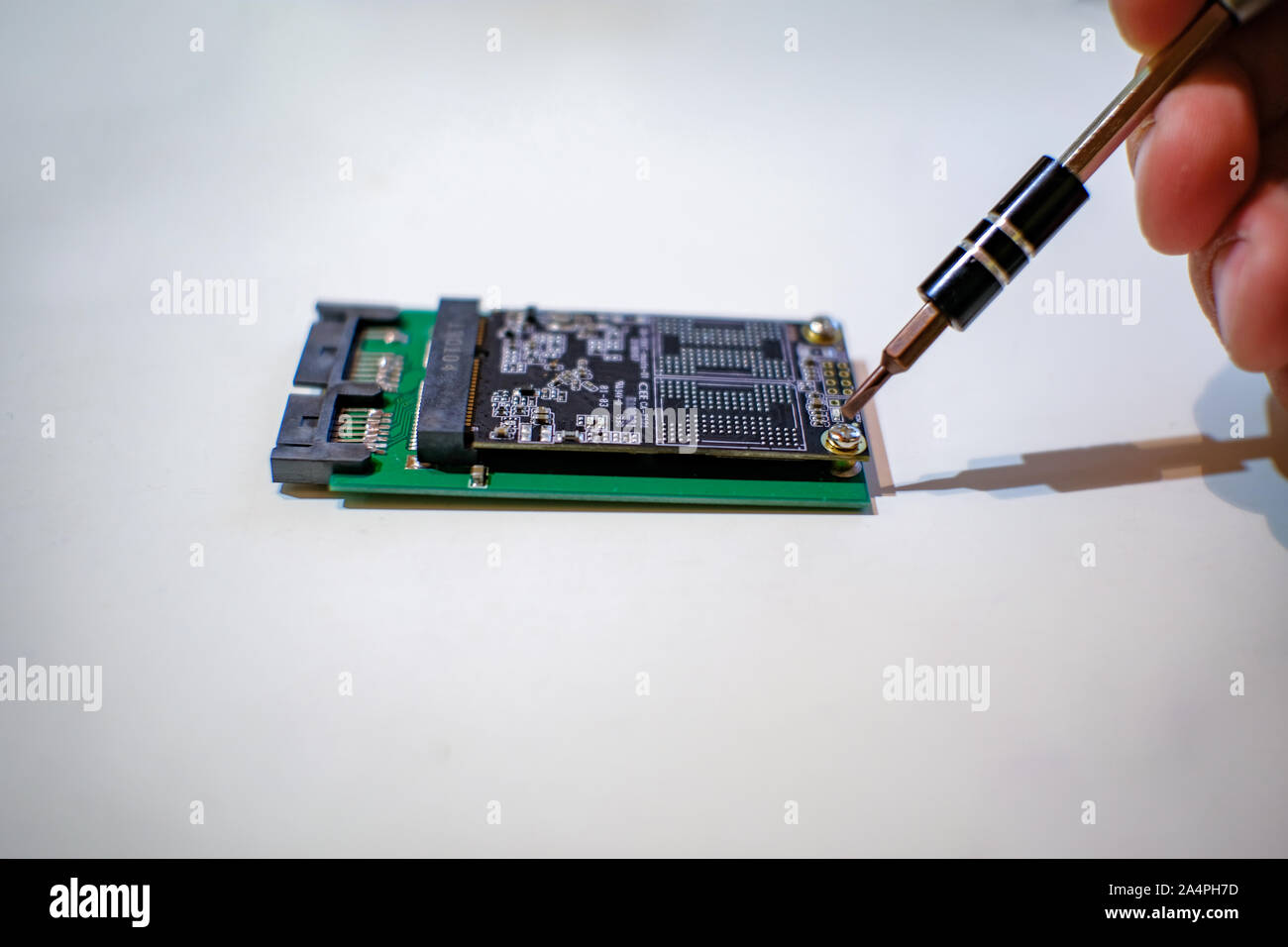Le mani umane lavorando su chipset ssd componenti di computer con un cacciavite Foto Stock