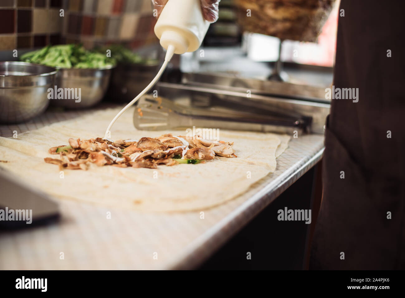 La cottura fajitos nella caffetteria. La cottura di shawarma in pita in cucina. Avvolgere il pollo, carote, lattuga, pomodoro in pane pita. Foto Stock