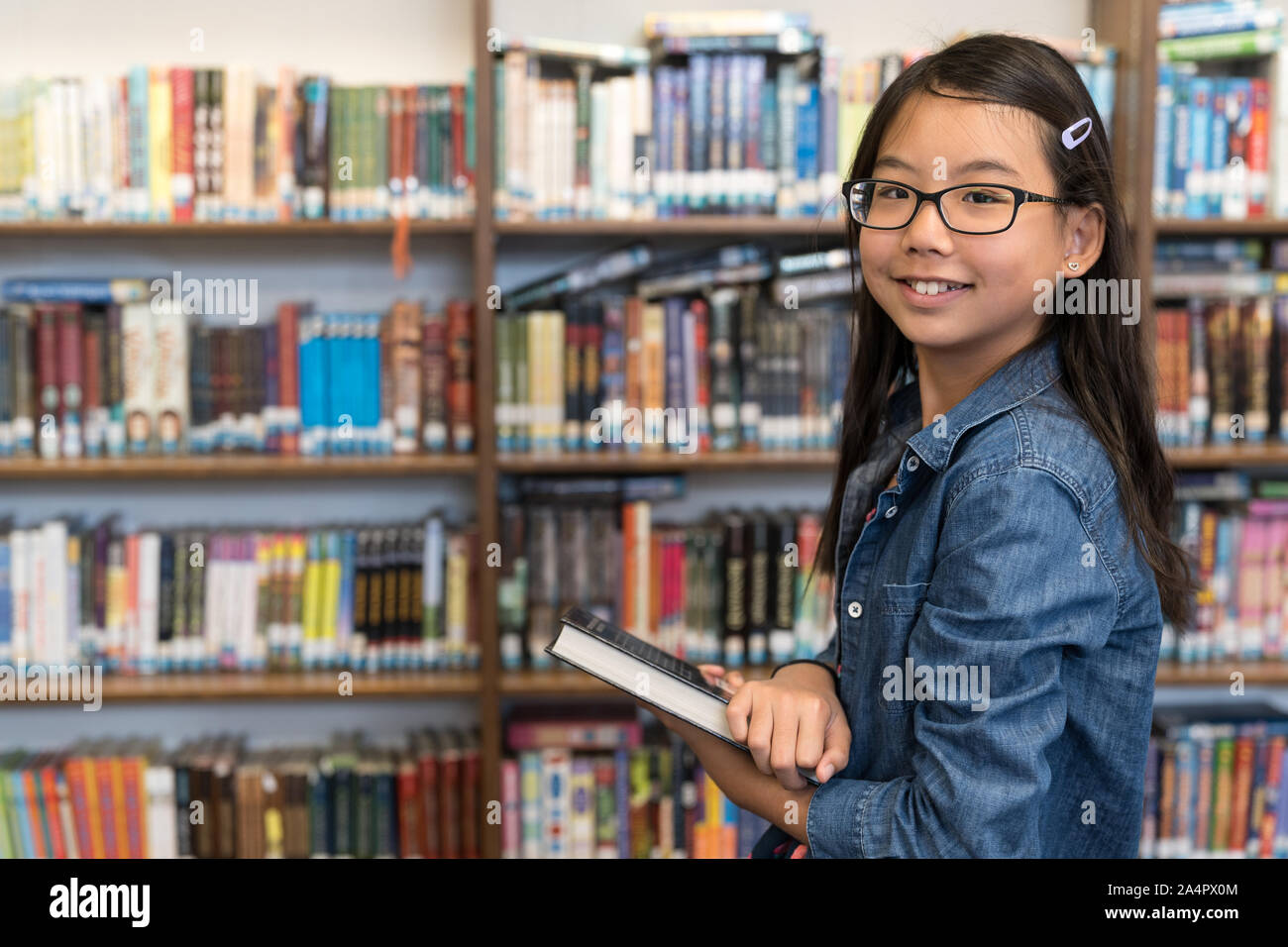 Asian ragazza adolescente con gli occhiali in biblioteca scolastica Foto Stock