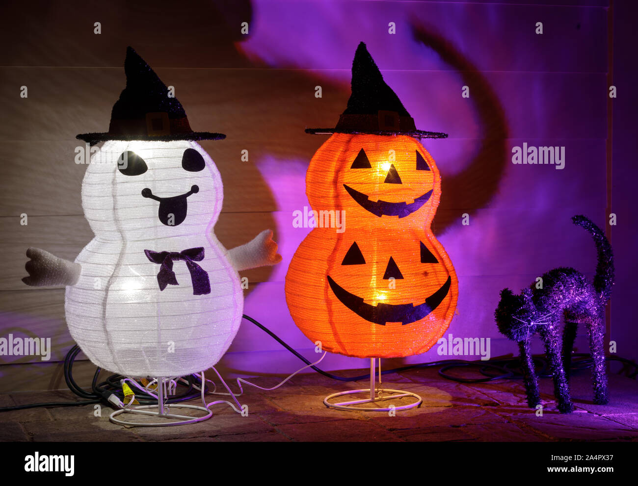 Illuminata di Halloween collassabile zucche impilate in cappelli di strega e un nero cat. Foto Stock
