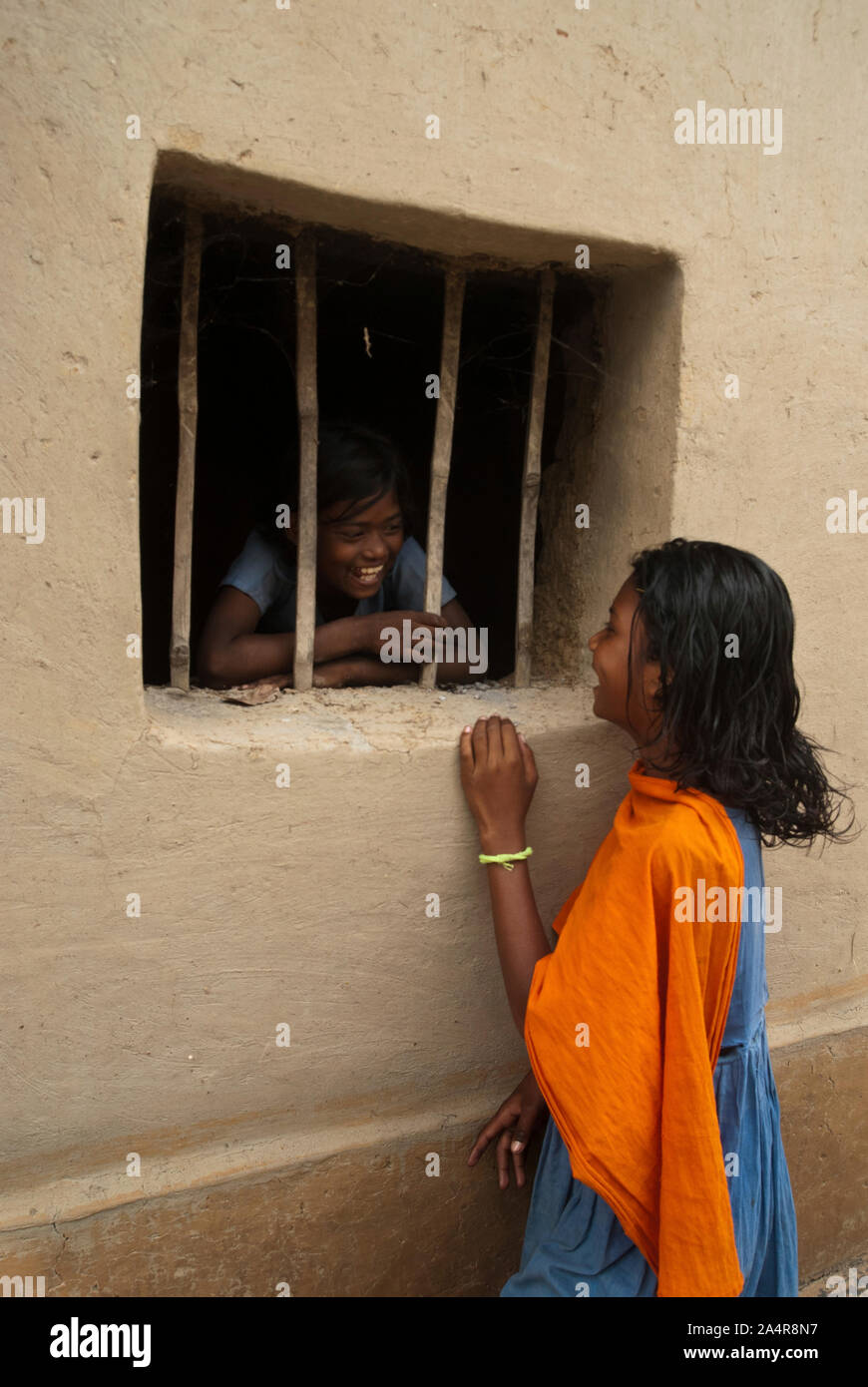 Un vivace ragazza di Santal comunità parla con il suo amico, dalla finestra della sua casa in Joypurhat, Rajshahi, Bangladesh. Il 20 maggio 2011..L'Santals sono una minoranza etnica a vivere in una comunità in diversi distretti di Rajshahi divisione in Bangladesh. La maggior parte non proprio a terra e il lavoro come tutti i giorni pagati operai per retribuzioni molto basse. Gran parte dei miglioramenti apportati in termini di tecnologia hanno bypassato queste comunità isolate dove dominano i maschi e le donne sostenere il fardello di agricoltura e di effettuare altri mezzi di sussistenza.Santals sono anche il gruppo etnico in India dove hanno insediamenti negli Stati Uniti o Foto Stock