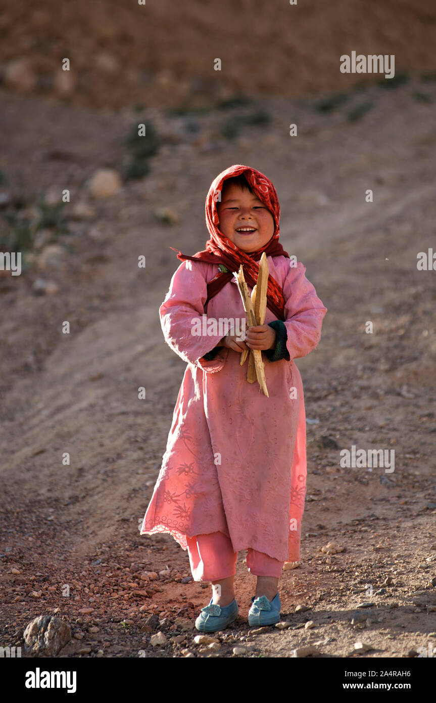 Una giovane ragazza afgana holding alcuni di legna da ardere, sorride alla telecamera, nel villaggio di rag-e-Shad, nella periferia della città di Bamyan, nella provincia di Mazar-i-Sharif, Afghanistan. Il 11 maggio 2009. Foto Stock