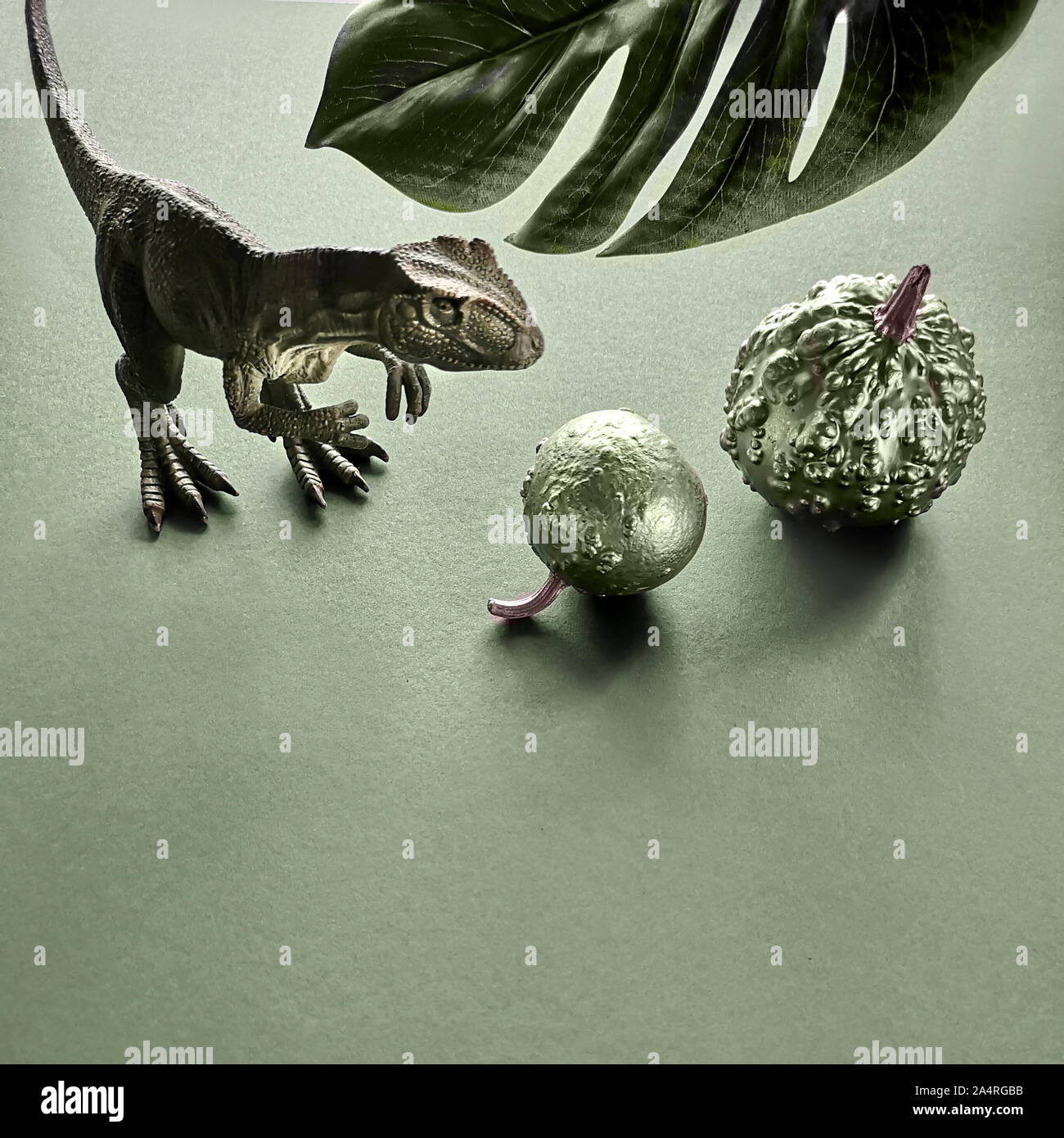 Dinosauro e zucche di Halloween su erba cipollina sfondo verde con foglia esotici con copy-spazio, tonica immagine, composizione quadrata Foto Stock