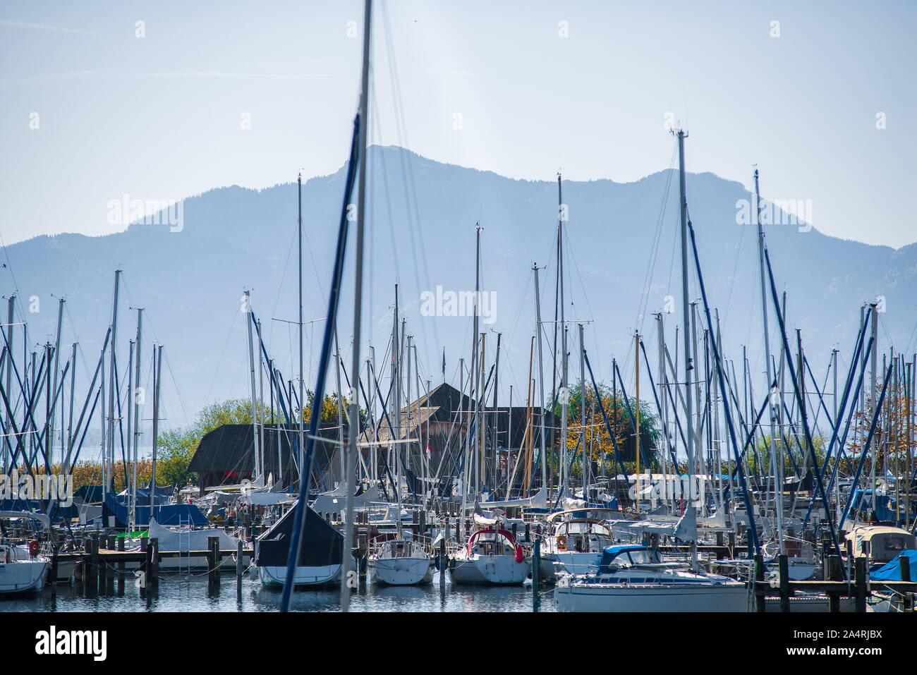 Vista delle barche a vela ormeggiata in un lago con sullo sfondo le Alpi Foto Stock