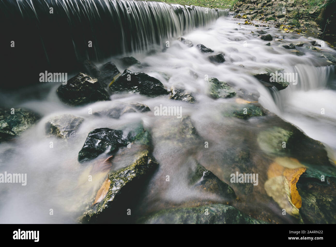 Una piccola cascata con fogliame Foto Stock